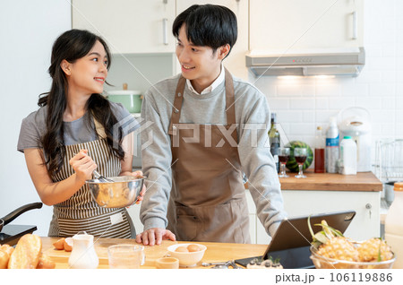 A beautiful Asian girlfriend is making pancakes in the kitchen with her boyfriend A beautiful Asian girlfriend is making pancakes in the kitchen with her boyfriend 106119886