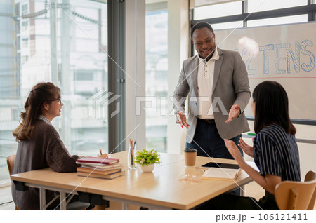 An African American male teacher teaching English for Asian students at a language school. 106121411