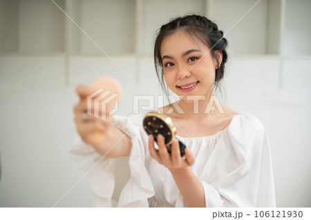 An attractive Asian female beauty influencer showing her new cosmetic product to a camera 106121930