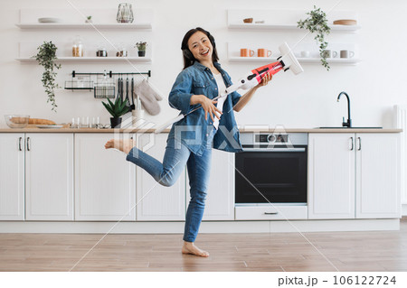 Woman imitating guitar player with cordless vacuum at home 106122724