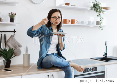 Female cook tasting vegetarian meal in kitchen interior Female cook tasting vegetarian meal in kitchen interior 106123483