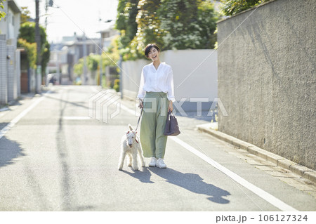 愛犬のワイヤーフォックステリアと住宅街を散歩する若い女性 106127324