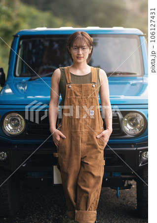 青い車の前でポケットに手を入れこちらを見てる女性 106127431