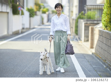 愛犬のワイヤーフォックステリアと住宅街を散歩する若い女性 愛犬のワイヤーフォックステリアと住宅街を散歩する若い女性 106128272