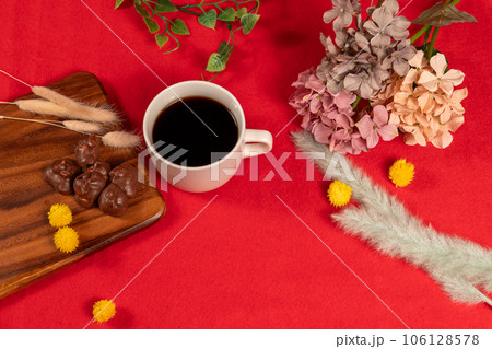 赤い絨毯に配置されたコーヒーとチョコレート、冬っぽいドライフラワーを添えて 赤い絨毯に配置されたコーヒーとチョコレート、冬っぽいドライフラワーを添えて 106128578