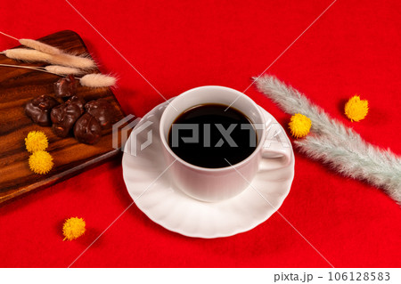 赤い絨毯に配置されたコーヒーとチョコレート、冬っぽいドライフラワーを添えて 106128583