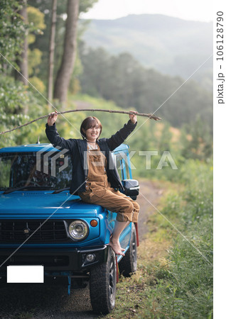 青い車のボンネットに座り棒を両手で持ち上げてる 106128790