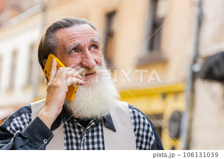Happy man grandfather having remote conversation talk on smartphone good news gossip in city street 106131039