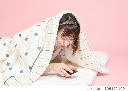 パジャマ姿でスマホを操作する女性 パジャマ姿でスマホを操作する女性 106131100
