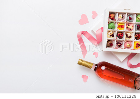 Bottle of red wine on colored background for Valentine Day with gift and chocolate. Heart shaped with gift box of chocolates top view with copy space Bottle of red wine on colored background for Valentine Day with gift and chocolate. Heart shaped with gift box of chocolates top view with copy space 106131229
