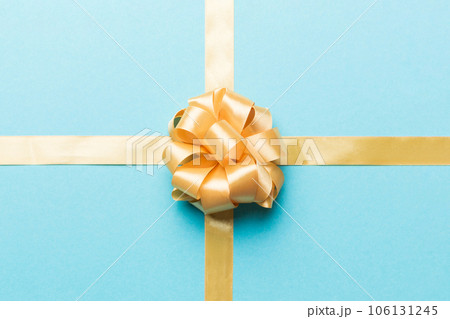 Top view of gold ribbon rolled and yellow bow isolated on colored background. Flat lay with copy space 106131245