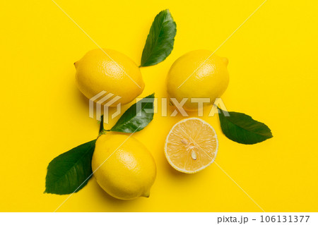 Many fresh ripe lemons with green leaves on colored background, top view, space for text 106131377