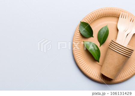 set of empty reusable disposable eco-friendly plates, cups, utensils on light white colored table background. top view. Biodegradable craft dishes. Recycling concept. Close-up set of empty reusable disposable eco-friendly plates, cups, utensils on light white colored table background. top view. Biodegradable craft dishes. Recycling concept. Close-up 106131429