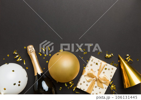 Flat lay composition of Champagne bottle gift box ribbons and confetti on colored background. Flat lay, top view holiday concept Flat lay composition of Champagne bottle gift box ribbons and confetti on colored background. Flat lay, top view holiday concept 106131445