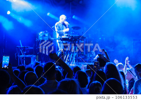 Male singer performing song on stage for group of fans 106133553