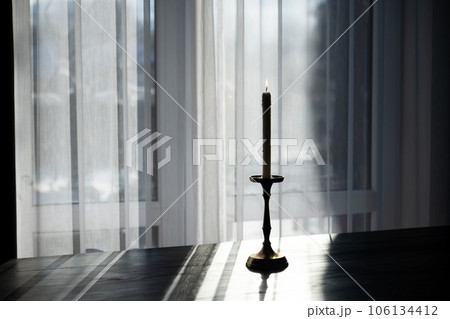 Lighting candle in a brass candlestick 106134412