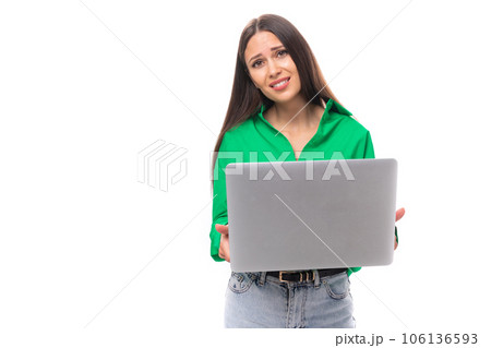young european brunette woman with brown eyes in green blouse works online using laptop young european brunette woman with brown eyes in green blouse works online using laptop 106136593