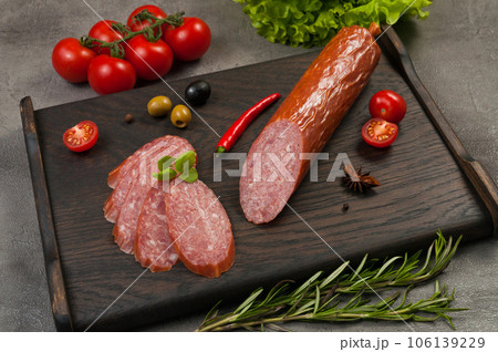 smoked sausage servelat or salami on a dark wooden background smoked sausage servelat or salami on a dark wooden background 106139229
