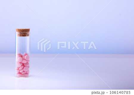 Pink pills in a glass bottle on a blue background. Health care, medical pills and nutritional supplements Pink pills in a glass bottle on a blue background. Health care, medical pills and nutritional supplements 106140785