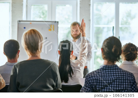 Male speaker giving talk at business meeting. Audience in conference hall. Rear view of business woman raising hand for speaker's question. 106141305