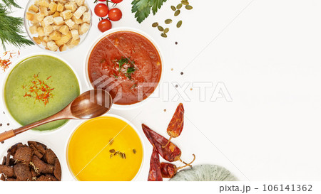 Food banner with set of different vegetable cream soups with wooden spoon on a white background with ingredients and copy space. Cozy meal, vegetarian healthy food. Top view 106141362