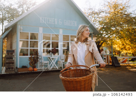 Beautiful woman with a bike on the background of a blue house in the fall. 106142493