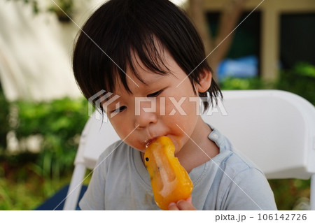 A child is eating a popsicle. A child is eating a popsicle. 106142726