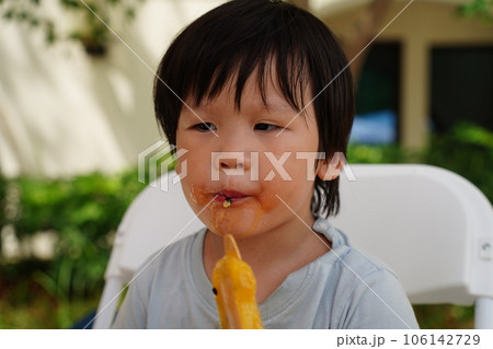 A child is eating a popsicle. 106142729