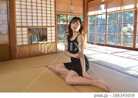 畳の上に座りくつろぐ黒いキャミソール姿の若い女性 106143039