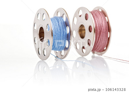 spools of blue and pink thread on a white background 106143328