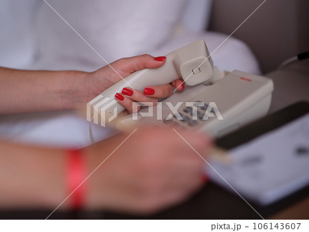 Woman dialing phone number on white landline phone in hotel Woman dialing phone number on white landline phone in hotel 106143607
