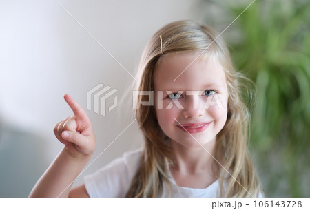 Portrait of cheerful smiling child girl points finger to side Portrait of cheerful smiling child girl points finger to side 106143728