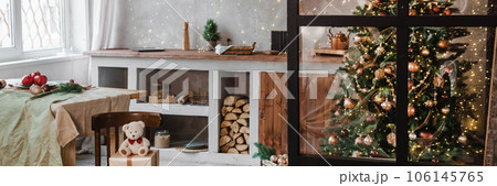 Home New Year's interior. Christmas tree with gifts, decorated with garlands in the kitchen. Cozy atmosphere of a home holiday, loft design of the room, Scandinavian style. 106145765