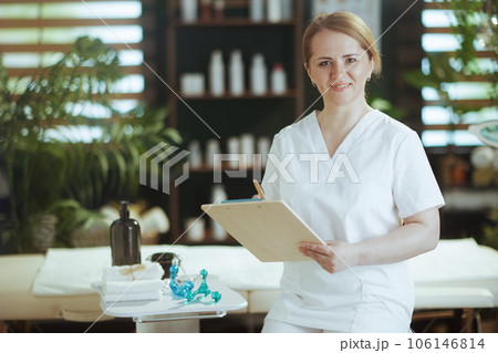 happy massage therapist woman in massage cabinet with clipboard happy massage therapist woman in massage cabinet with clipboard 106146814