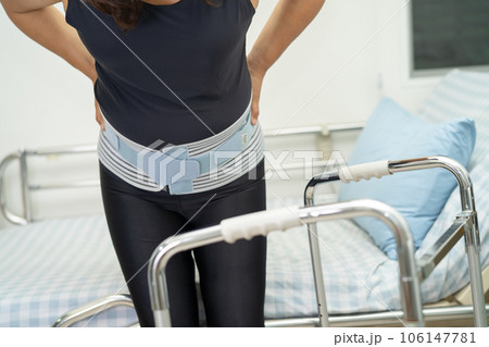 Asian lady patient wearing back pain support belt for orthopedic lumbar with walker. Asian lady patient wearing back pain support belt for orthopedic lumbar with walker. 106147781