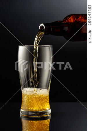 Pouring beer from a bottle into a glass. 106148505