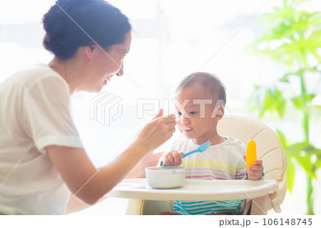 Baby eating solid foods in high chair. Baby eating solid foods in high chair. 106148745