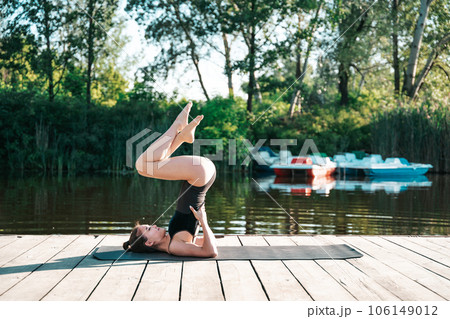 Yoga outdoors. Young woman practicing yoga on pier by the river. Healthy lifestyle, harmony and balance in body. 106149012