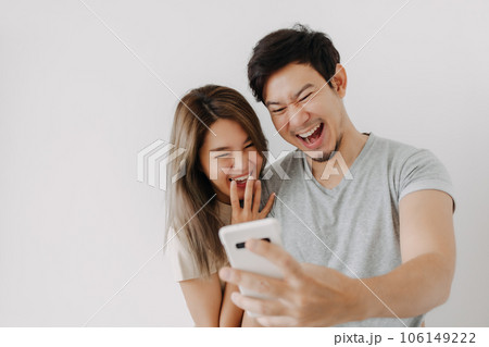 Funny couple lover laugh at the clip in the smartphone isolated on white. Funny couple lover laugh at the clip in the smartphone isolated on white. 106149222
