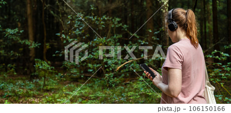 Young woman, walking in forest, nature, listening to music in headphones 106150166