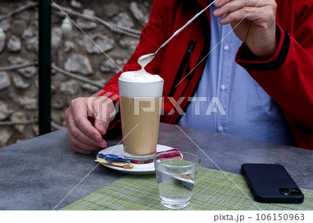 A glass of latte coffee, small glass of water and one smartphone. A glass of latte coffee, small glass of water and one smartphone. 106150963