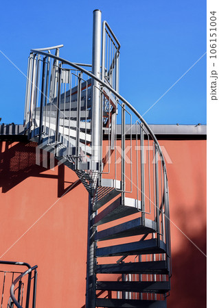 Staircase and shadow. Gray metal stairs next to the wall of the orange building. Staircase and shadow. Gray metal stairs next to the wall of the orange building. 106151004