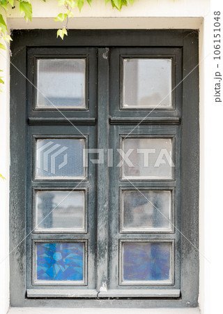 Old cracked wall with a window. window of old house. Old window with green frame. 106151048