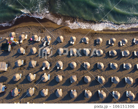 View from above, stunning aerial view of an amazing empty beach with white beach umbrellas and turquoise clear water with waves. 106151306