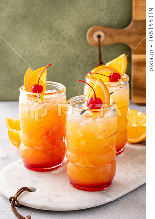 Rum punch in tiki glasses with orange slices and a cherry 106153019