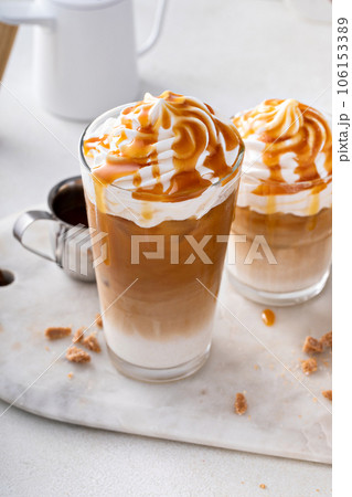 Iced caramel latte topped with whipped cream and caramel sauce 106153389