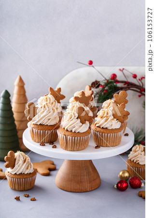 Gingerbread cupcakes with cream cheese frosting topped with gingerbread cookies 106153727
