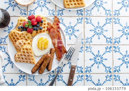 Breakfast plate with waffles, fried egg, bacon and sausage Breakfast plate with waffles, fried egg, bacon and sausage 106153779