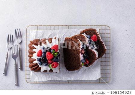 Chocolate pound cake topped with cream cheese glaze and berries 106154928