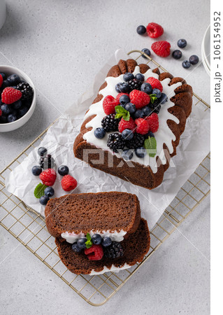 Chocolate pound cake topped with cream cheese glaze and berries Chocolate pound cake topped with cream cheese glaze and berries 106154952